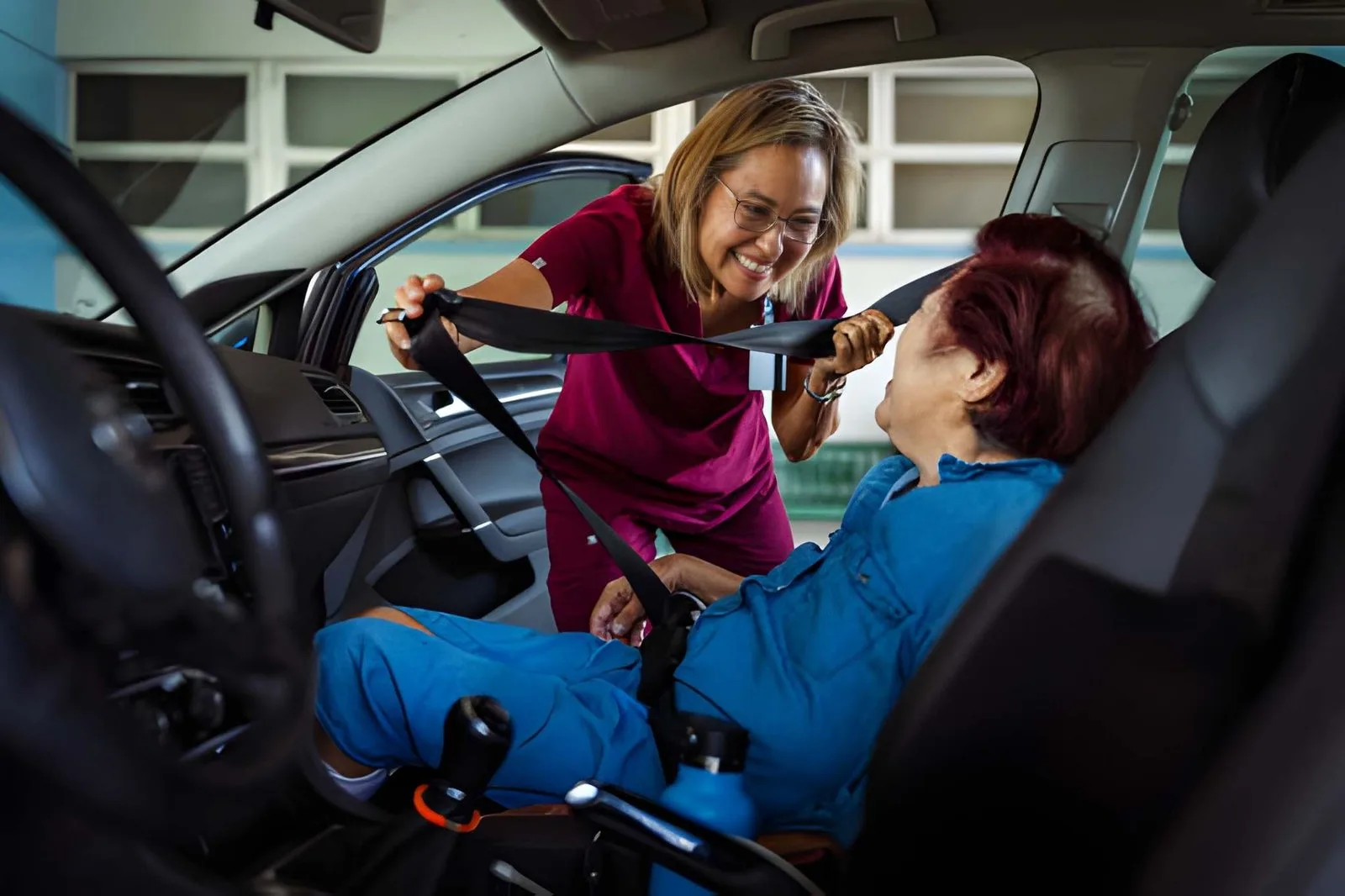 Caregiver helping an older adult get into a vehicle