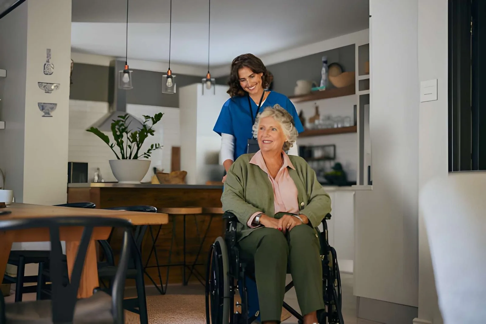 Caregiver supporting an older adult using a wheelchair at home
